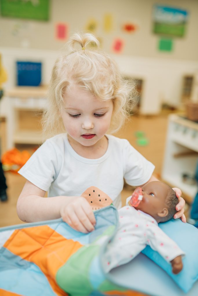 girl with baby doll at preschool