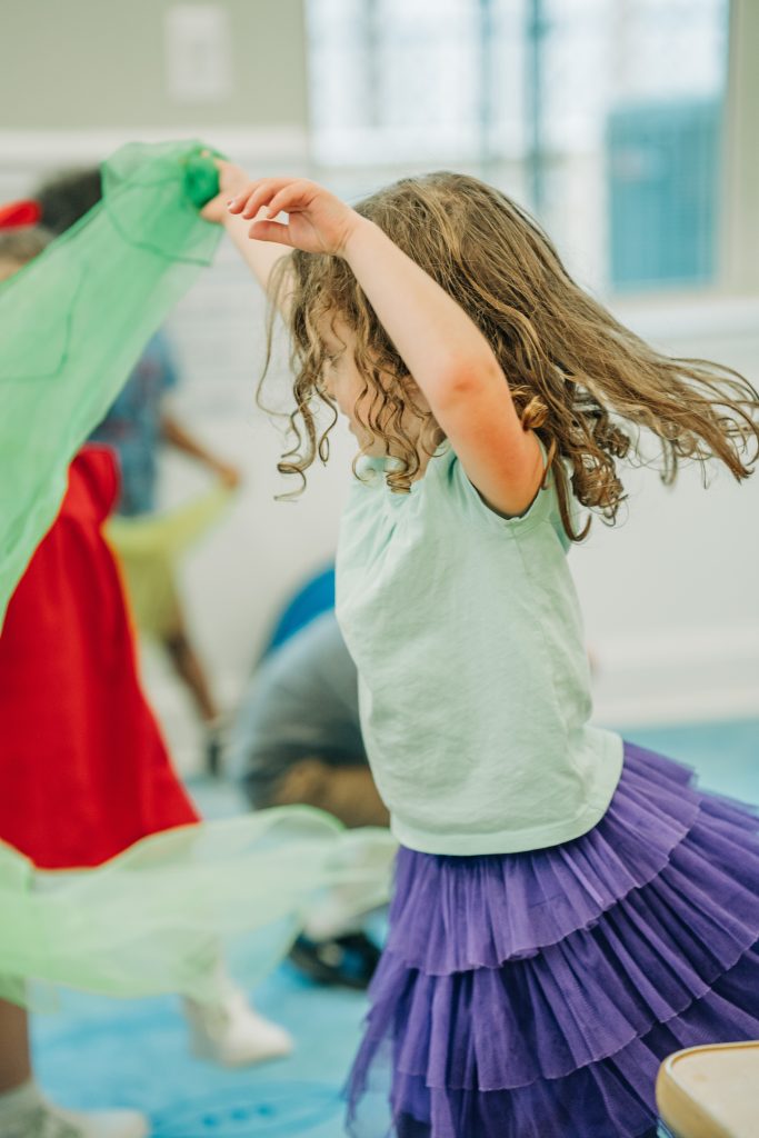 girl playing with sheet at preschool