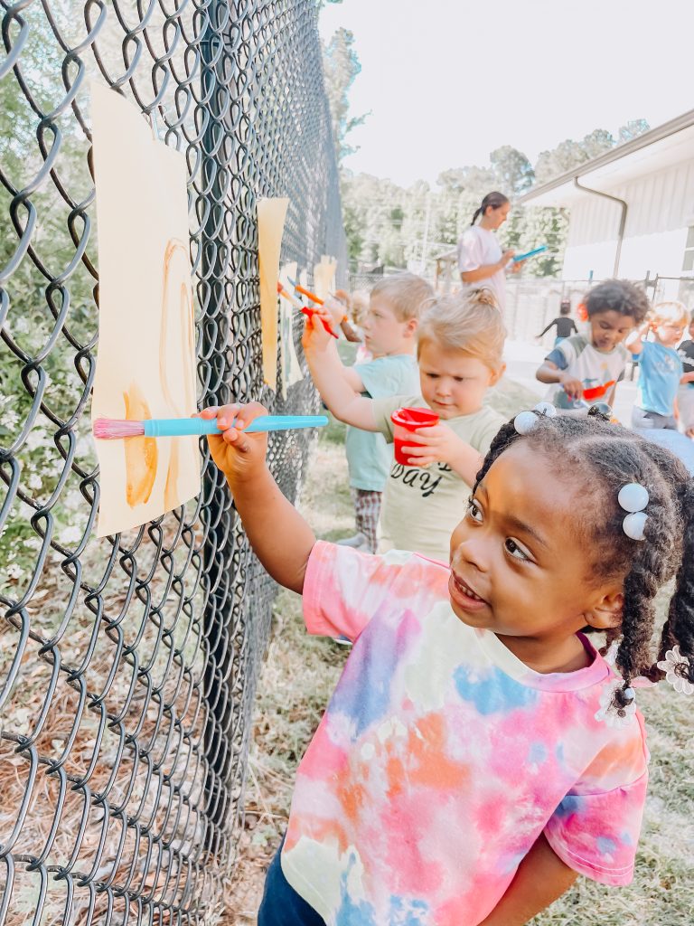 child painting outside at preschool